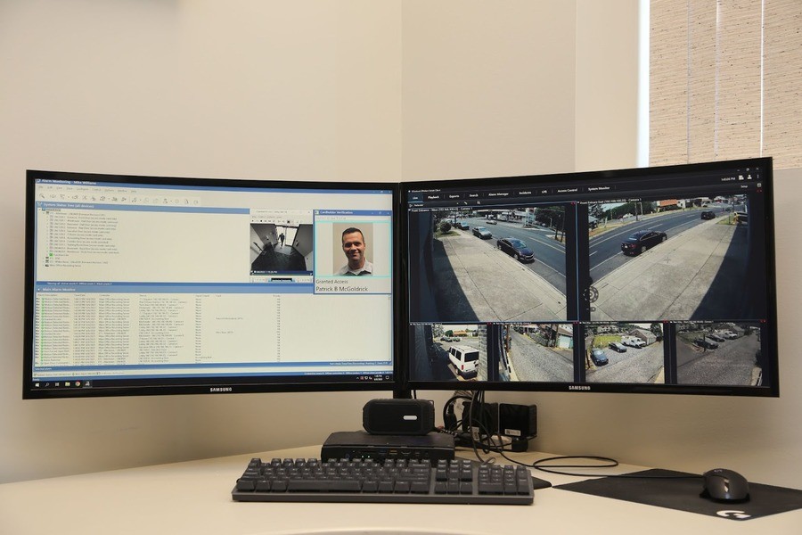Two computer monitors, one displaying security system software and the other displaying security camera footage.