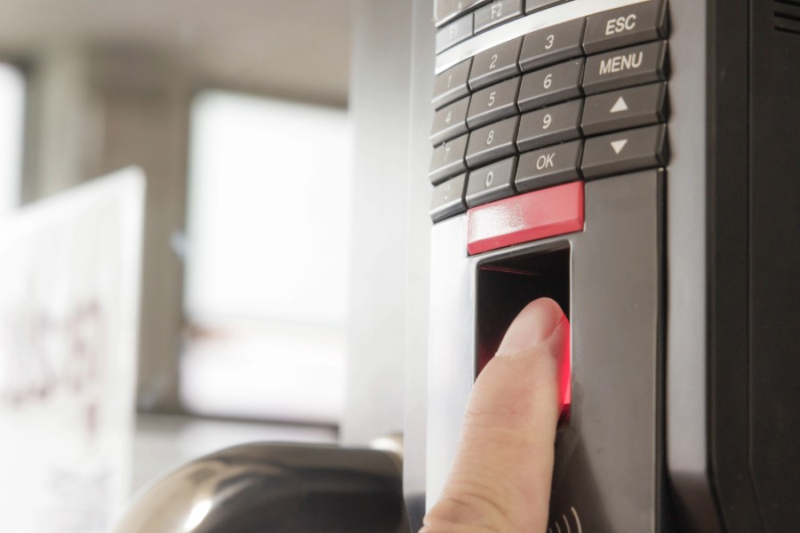 A person pressing a button on a fire alarm system on a wall keypad.