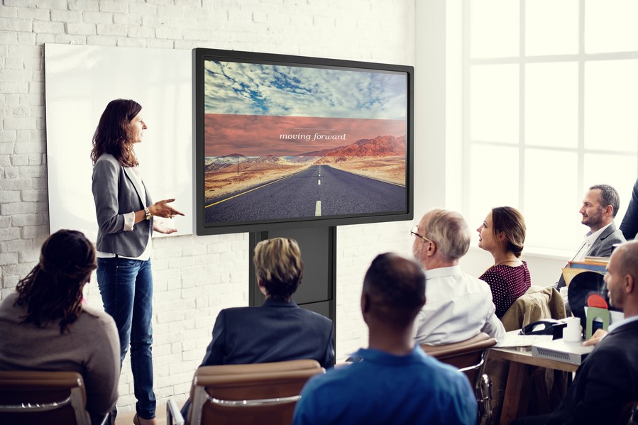 A person delivering a presentation to a small group using a vibrant display.