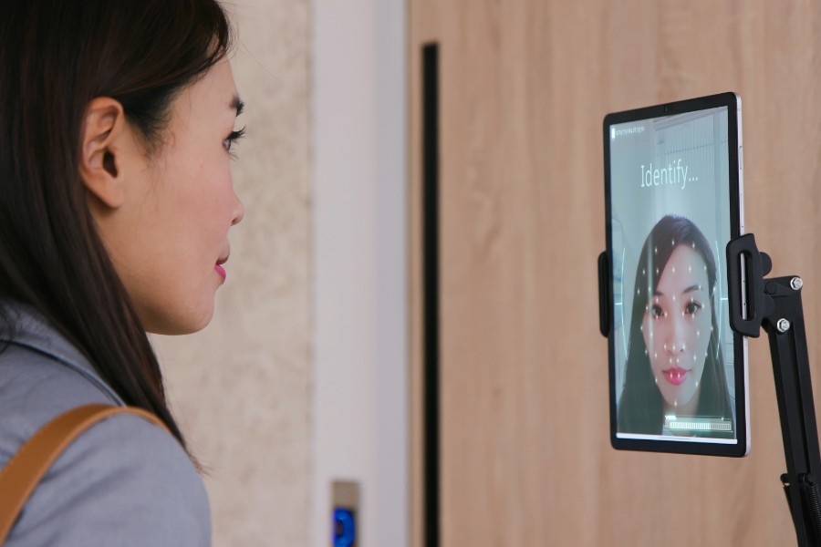 A woman using facial recognition technology to enter a building.